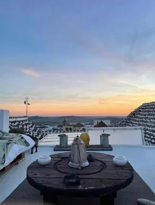 a table on the roof of a house with a sunset at Casa Antigua - Terraza con Vistas al Mar in Medina Sidonia