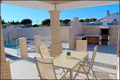 a patio with a table and chairs on a patio at Chalet Peñuelas con piscina in Conil de la Frontera