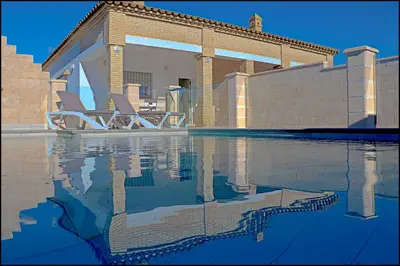 a swimming pool with two lounge chairs next to a house at Chalet Peñuelas con piscina in Conil de la Frontera