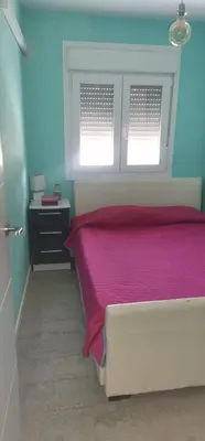 a bedroom with a pink bed and two windows at Modern Seaside Apartment 700 mt from beach in El Puerto de Santa María