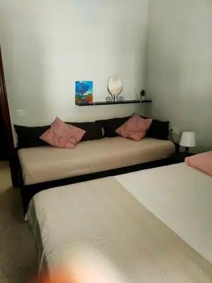 two beds in a room with a couch at Apartamento en pleno centro de Cadiz con parking economico in Cádiz