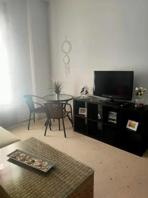a living room with a tv and a table with chairs at Apartamento en pleno centro de Cadiz con parking economico in Cádiz