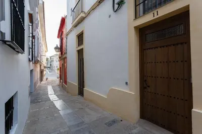 a narrow alley with a wooden door in a building at Semiloft Romantico Catedral con soleada azotea comunitaria in Jerez de la Frontera