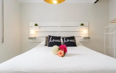 a white bed with a bouquet of flowers on it at Apartamento semi-industrial palacio Castilla in Jerez de la Frontera