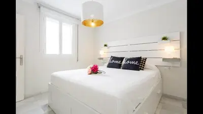 a white bedroom with a white bed with flowers on it at Apartamento semi-industrial palacio Castilla in Jerez de la Frontera