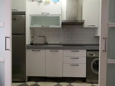 a kitchen with white cabinets and a sink and a refrigerator at APARTAMENTO APODACA in Cádiz