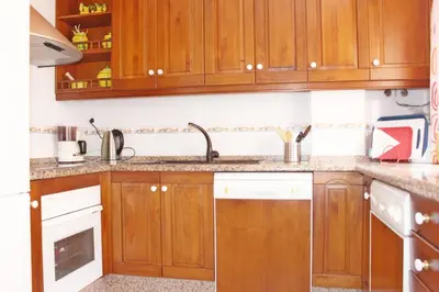 a kitchen with wooden cabinets and a sink at Casa Valdelagrana Playa in El Puerto de Santa María
