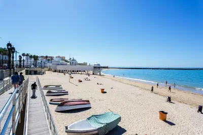 a beach with chaise lounges and boats on it at La Sorpresa del GENOVES by Cadiz4Rentals in Cádiz
