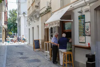 two older men standing outside of a shop on a street at La Sorpresa del GENOVES by Cadiz4Rentals in Cádiz