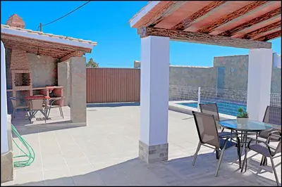 a patio with a table and chairs and a pergola at Chalet Ermita in Conil de la Frontera