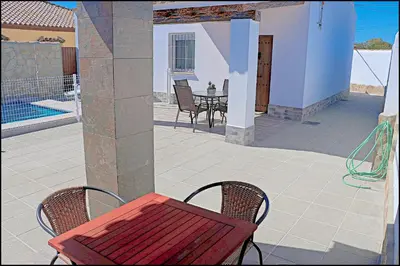 a red table and two chairs on a patio at Chalet Ermita in Conil de la Frontera