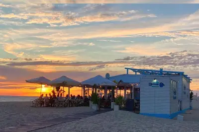 a restaurant on the beach with the sunset in the background at Romántica vista al paseo marítimo de Cádiz in Cádiz