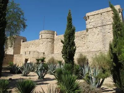 an old stone building with trees and plants at Apartamento Centro San Diego in Sanlúcar de Barrameda