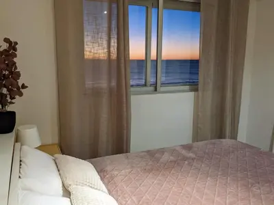 a bedroom with a bed and a window with the ocean at Apartamento en la playa con garaje in Cádiz
