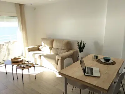 a living room with a couch and a table with a laptop at Apartamento en la playa con garaje in Cádiz