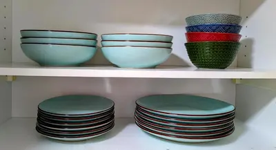 four bowls and plates sitting on a shelf at Apartamento en la playa con garaje in Cádiz