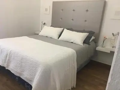 a bedroom with a white bed with a large headboard at Charming House + Chiclana de la Frontera + Garden in Chiclana de la Frontera