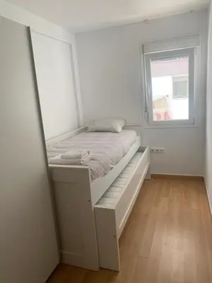 a small bedroom with a bed and a mirror at Duplex a 3 minutos de playa de la victoria Cadiz in Cádiz