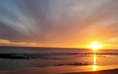 a sunset on the beach with the sun setting at Duplex a 3 minutos de playa de la victoria Cadiz in Cádiz