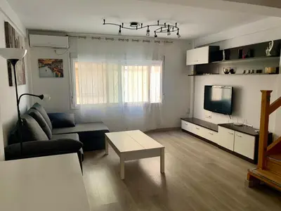 a living room with a couch and a tv at Duplex a 3 minutos de playa de la victoria Cadiz in Cádiz