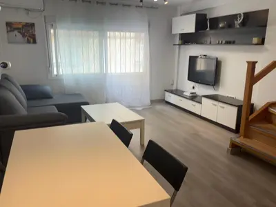 a living room with a table and a tv at Duplex a 3 minutos de playa de la victoria Cadiz in Cádiz