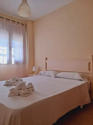 a bedroom with a large white bed with towels on it at Apartamentos Coto de San José in Chiclana de la Frontera