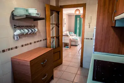 a kitchen with a counter and a room with a couch at Apartamentos Coto de San José in Chiclana de la Frontera