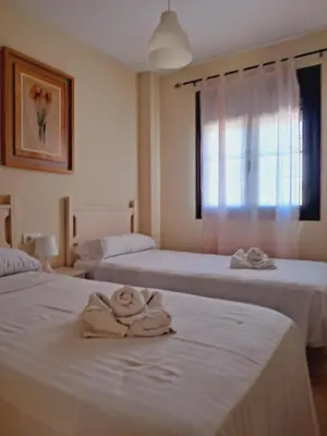 two beds in a room with towels on them at Apartamentos Coto de San José in Chiclana de la Frontera