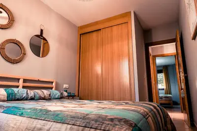 a bedroom with a bed and a wooden closet at Apartamentos Coto de San José in Chiclana de la Frontera