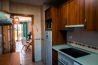 a kitchen with wooden cabinets and a stove top oven at Apartamentos Coto de San José in Chiclana de la Frontera