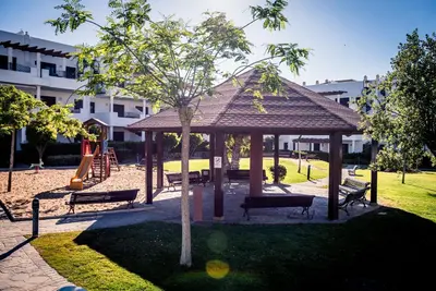 a park with a gazebo with benches and a playground at Apartamentos Coto de San José in Chiclana de la Frontera