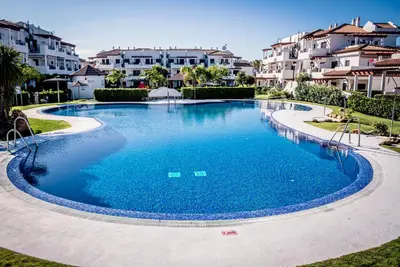a large swimming pool in front of some houses at Apartamentos Coto de San José in Chiclana de la Frontera