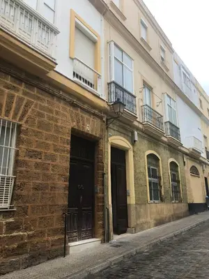 a brick building with windows and doors on a street at Spacious apartment in Cádiz 130 m² with balcony and city view in Cádiz