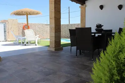 a patio with a table and chairs and an umbrella at Chalet carril de los pareja in Conil de la Frontera