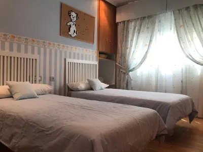 a bedroom with two beds and a window with curtains at Bahía blanca SM in Cádiz