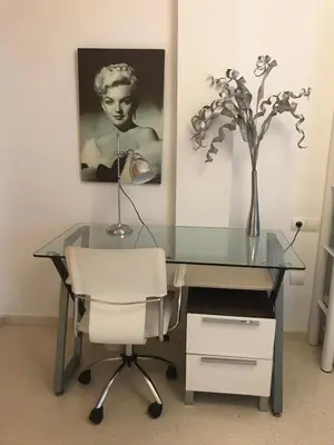 a glass desk with a chair and a vase of flowers at Apartamento Cadiz de Cine in Cádiz