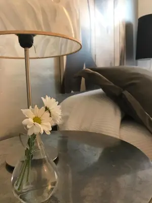 a vase with flowers on a table next to a bed at Apartamento Cadiz de Cine in Cádiz