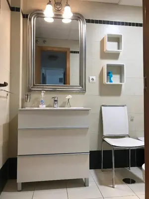a bathroom with a sink and a mirror and a chair at Apartamento Cadiz de Cine in Cádiz