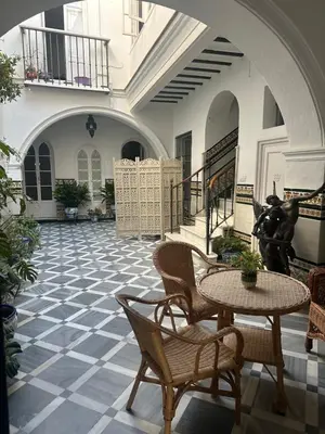 a courtyard with a table and chairs in a building at Lujosa suite privada en casa del S XIX in Sanlúcar de Barrameda
