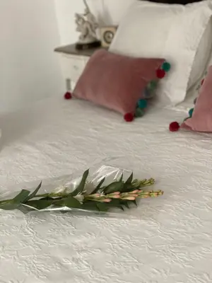 a flower laying on a white bed with pillows at Lujosa suite privada en casa del S XIX in Sanlúcar de Barrameda