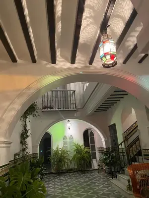 a building with a hallway with plants and a chandelier at Lujosa suite privada en casa del S XIX in Sanlúcar de Barrameda