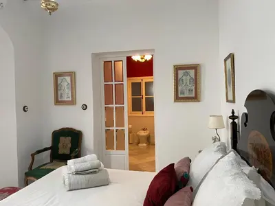 a bedroom with a bed and a door to a bathroom at Lujosa suite privada en casa del S XIX in Sanlúcar de Barrameda