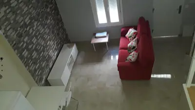 a living room with a red chair and a table at Duplex Daises in San Fernando