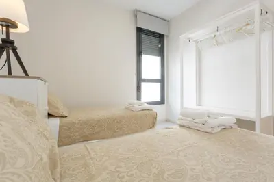 a white room with two beds and a window at Real Escuela Home in Jerez de la Frontera