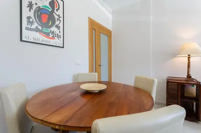 a dining room with a wooden table and white chairs at Real Escuela Home in Jerez de la Frontera