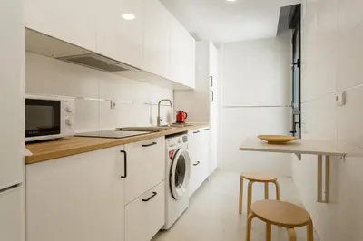 a kitchen with white cabinets and a washer and dryer at Real Escuela Home in Jerez de la Frontera