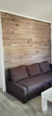 a brown couch in a room with a wooden wall at LA BARROSA-NOVO SANCTI PETRI, wifi, aire acondicionado, parking in Chiclana de la Frontera