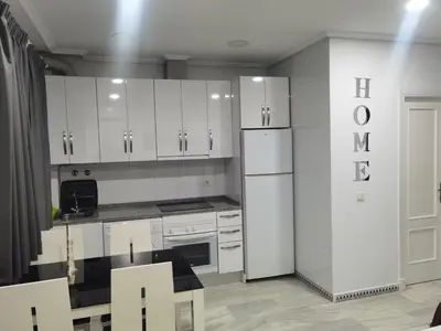 a kitchen with white cabinets and a refrigerator at LA BARROSA-NOVO SANCTI PETRI, wifi, aire acondicionado, parking in Chiclana de la Frontera