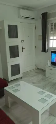 a living room with a white table and a tv at LA BARROSA-NOVO SANCTI PETRI, wifi, aire acondicionado, parking in Chiclana de la Frontera