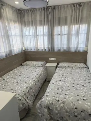 two beds in a small bedroom with curtains at LA BARROSA-NOVO SANCTI PETRI, wifi, aire acondicionado, parking in Chiclana de la Frontera